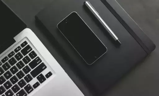 Zdjęcie przedstawia klawiaturą laptopa oraz leżacy obok telefon i rysik